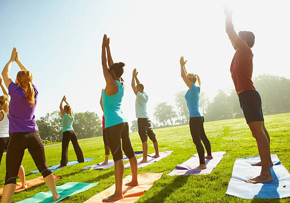 Young group of sportspeople taking a yoga class outdoors